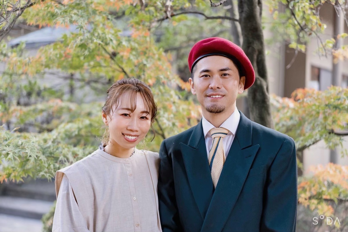 紅葉の下で寄り添う髙須賀夫妻のポートレート